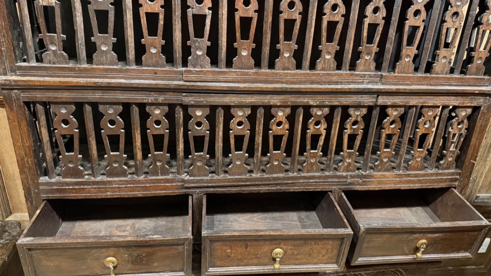 A dark oak seventeenth-century hanging cupboard featuring two upper tiers with carved pierced balusters and three small drawers with teardrop handles along the base. View X