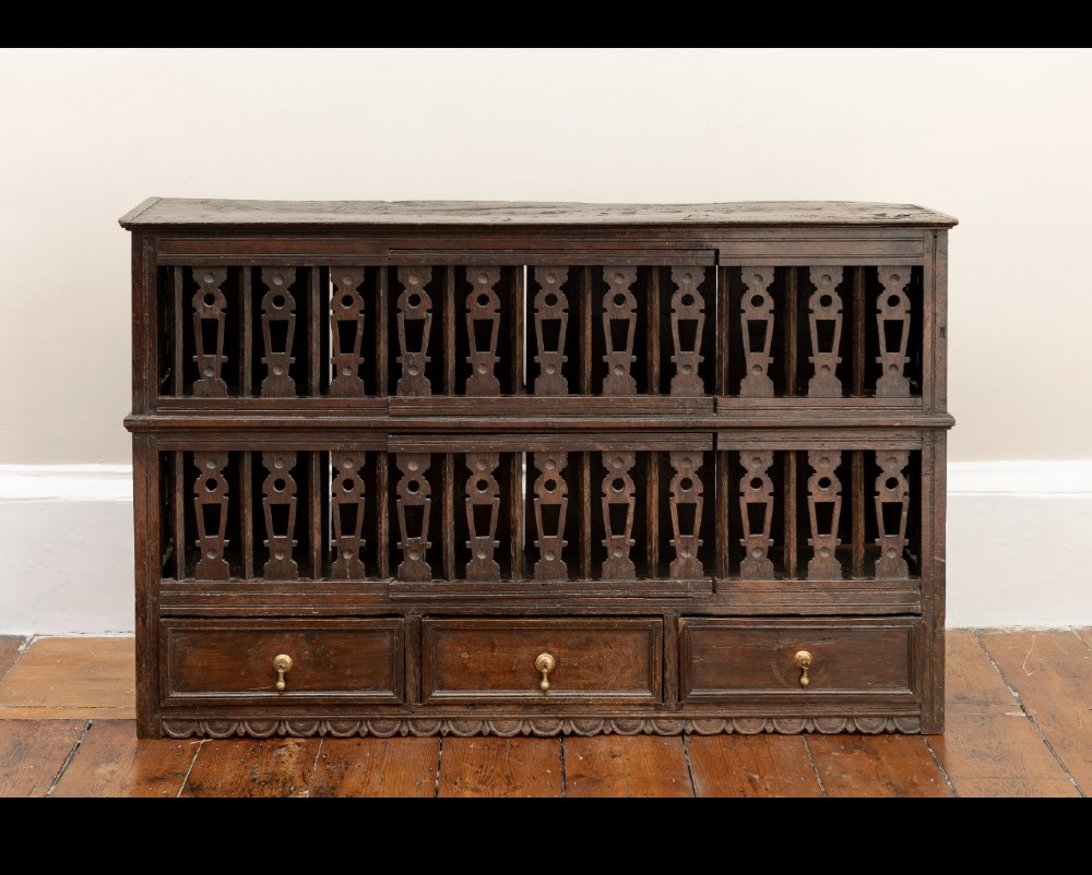 A dark oak seventeenth-century hanging cupboard featuring two upper tiers with carved pierced balusters and three small drawers with teardrop handles along the base. View XII