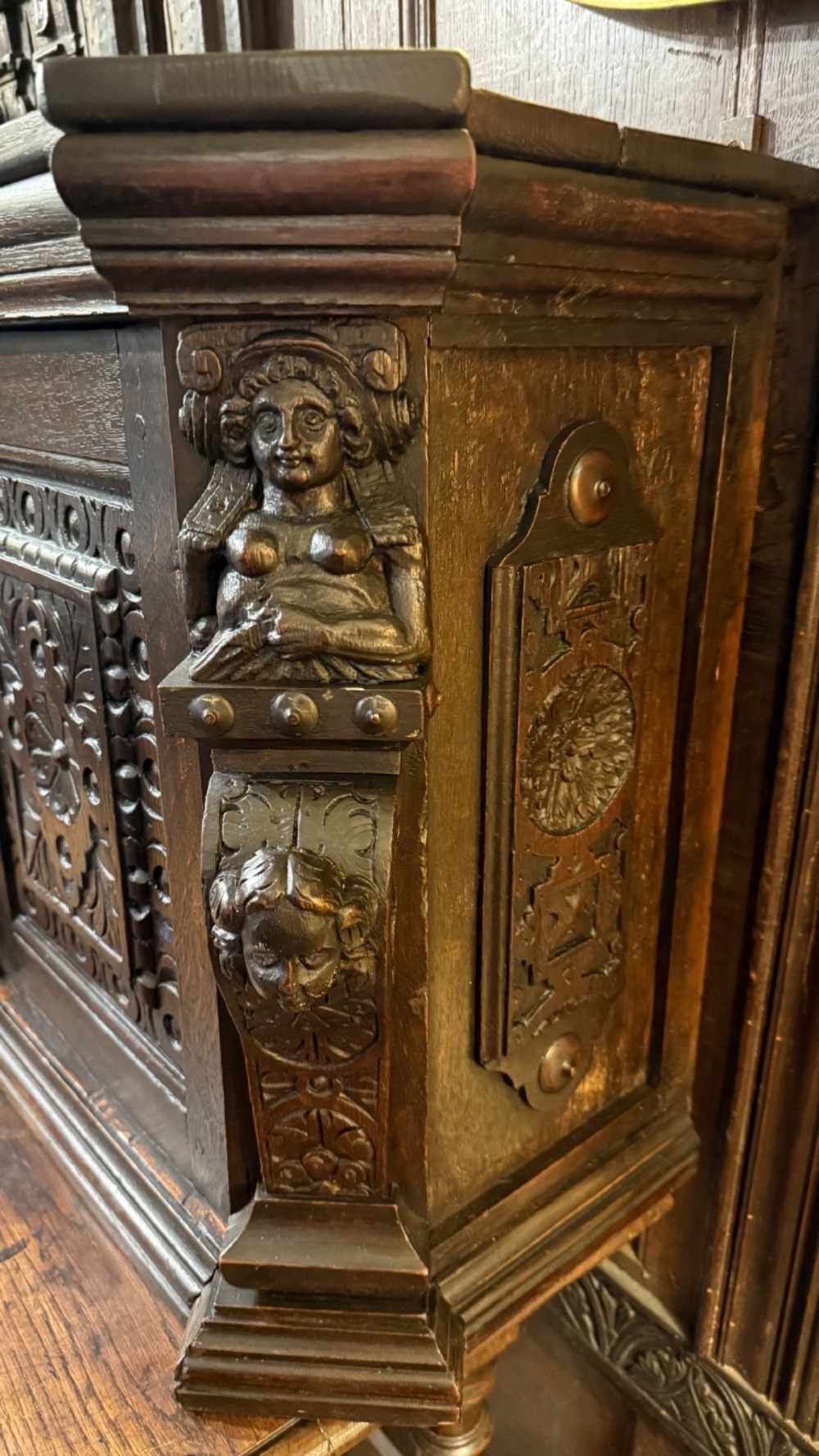 An 18th-century dark oak hanging cupboard featuring carved figural columns, relief door panels with floral motifs, and carved masks. View IV