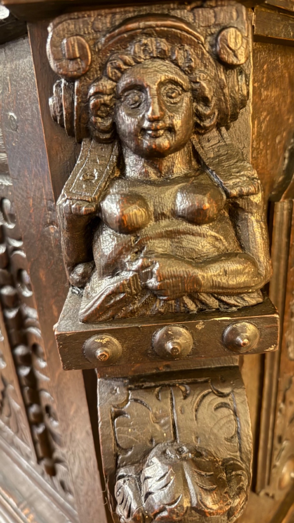 An 18th-century dark oak hanging cupboard featuring carved figural columns, relief door panels with floral motifs, and carved masks. View X