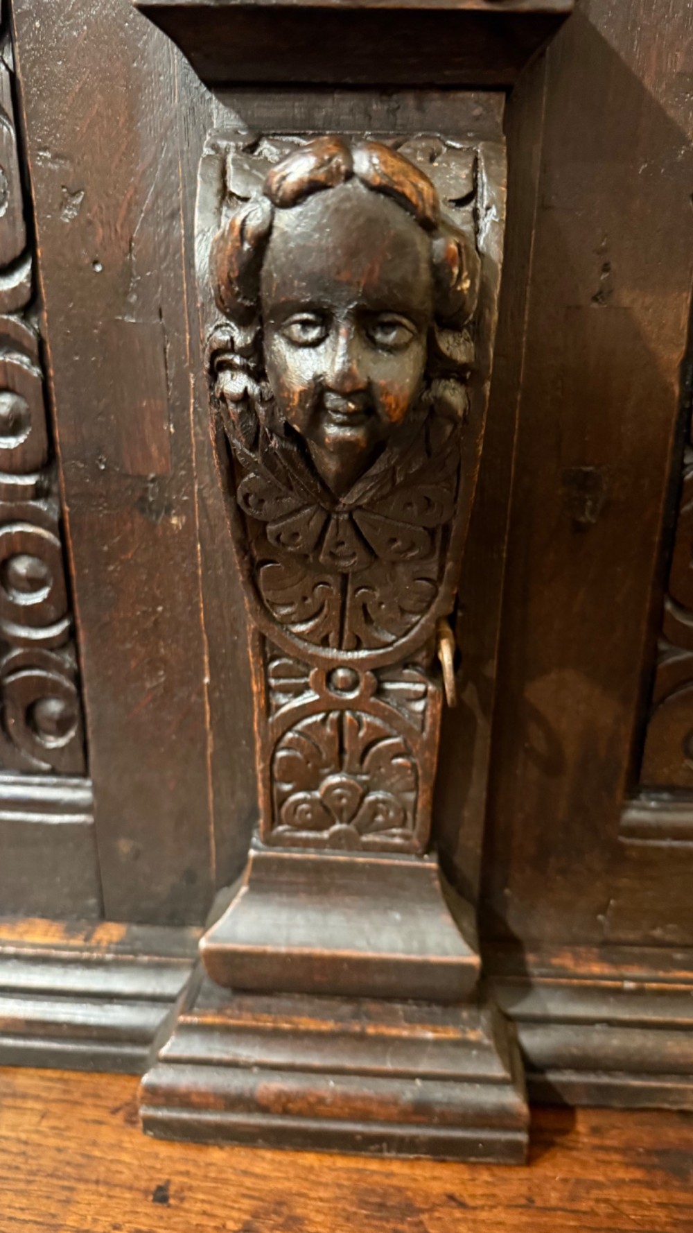 An 18th-century dark oak hanging cupboard featuring carved figural columns, relief door panels with floral motifs, and carved masks. View XIII