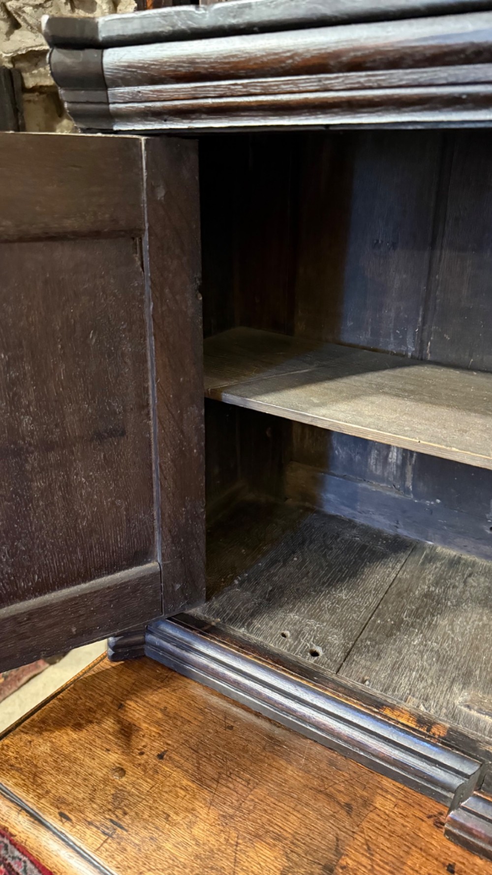 An 18th-century dark oak hanging cupboard featuring carved figural columns, relief door panels with floral motifs, and carved masks. View XV
