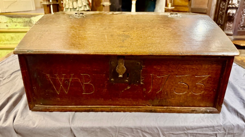 An 18th-century oak Bible box featuring a sloped hinged lid, incised initials WB, the date 1733, and a central iron lock plate.