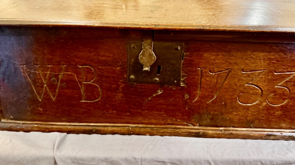 An 18th-century oak Bible box featuring a sloped hinged lid, incised initials WB, the date 1733, and a central iron lock plate. View V