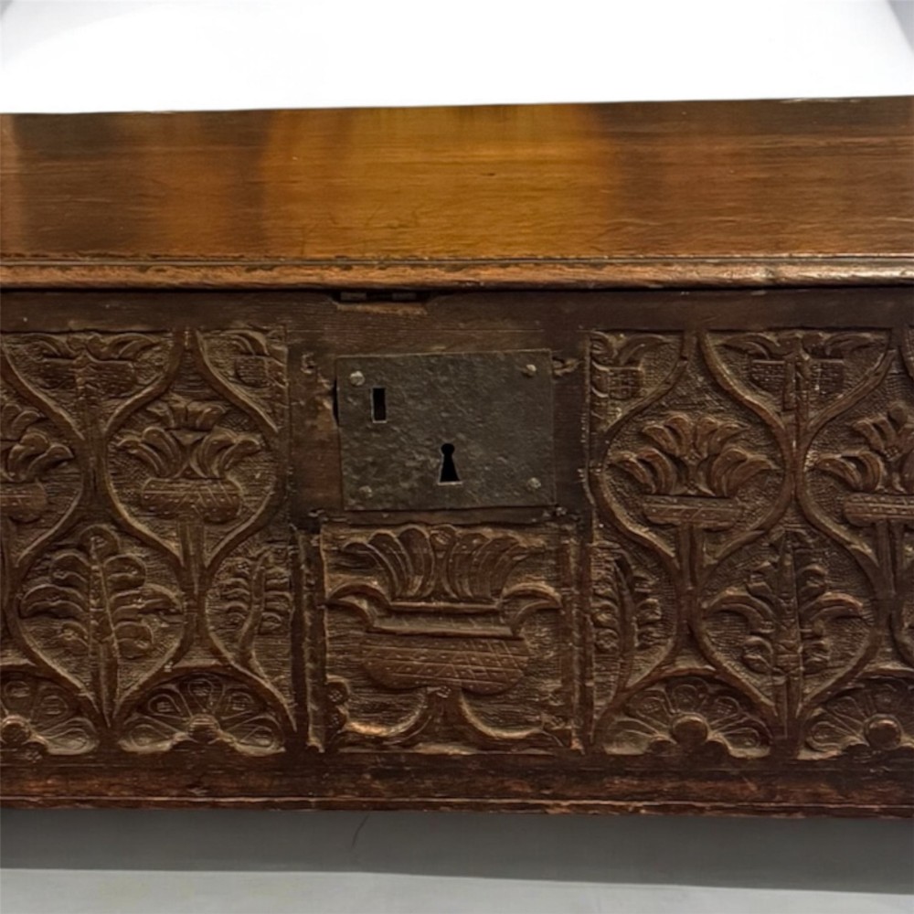 A 17th-century English oak bible box featuring relief carvings of foliate patterns across the front panel and a central iron lock plate. View III