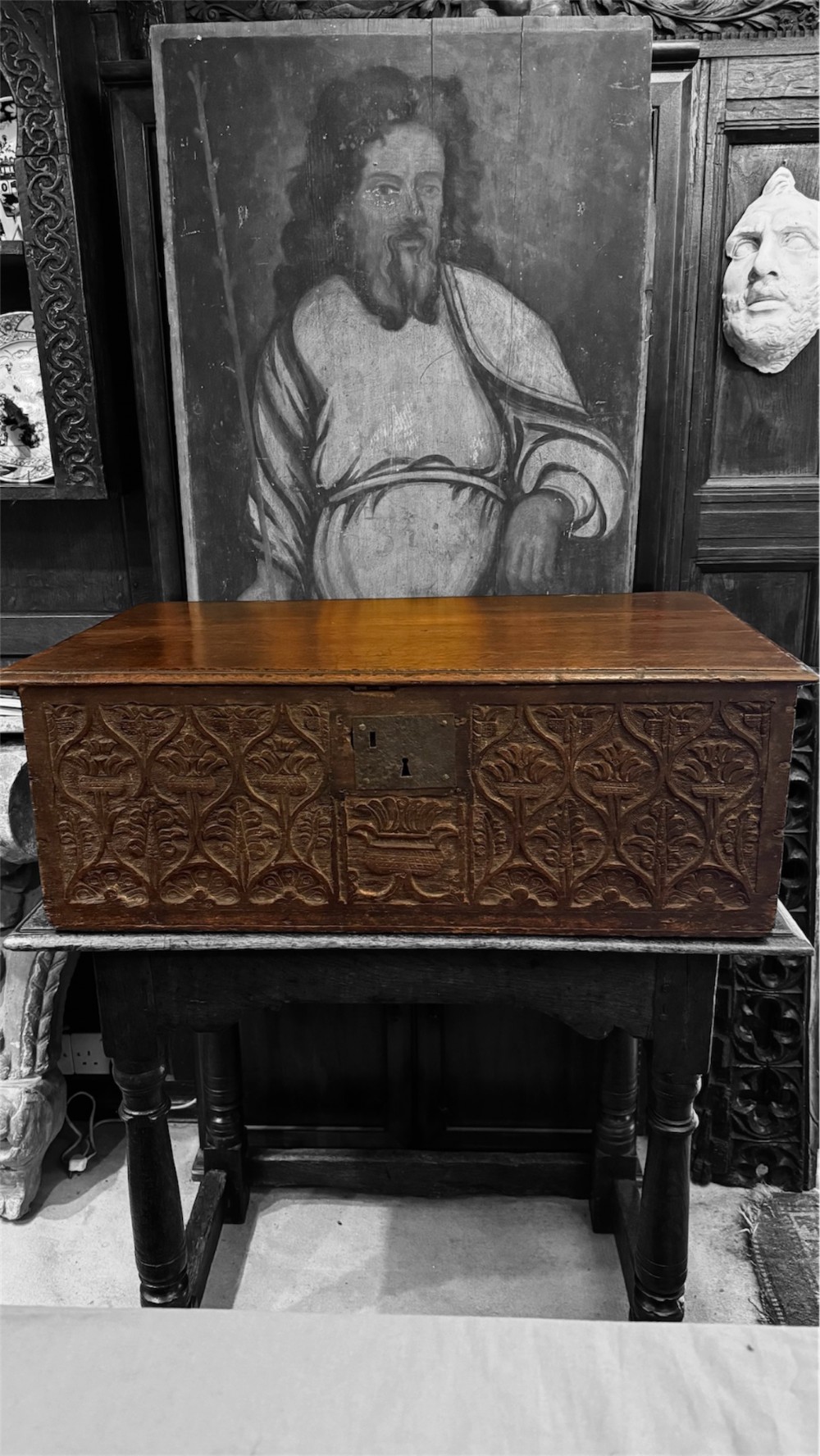 A 17th-century English oak bible box featuring relief carvings of foliate patterns across the front panel and a central iron lock plate.