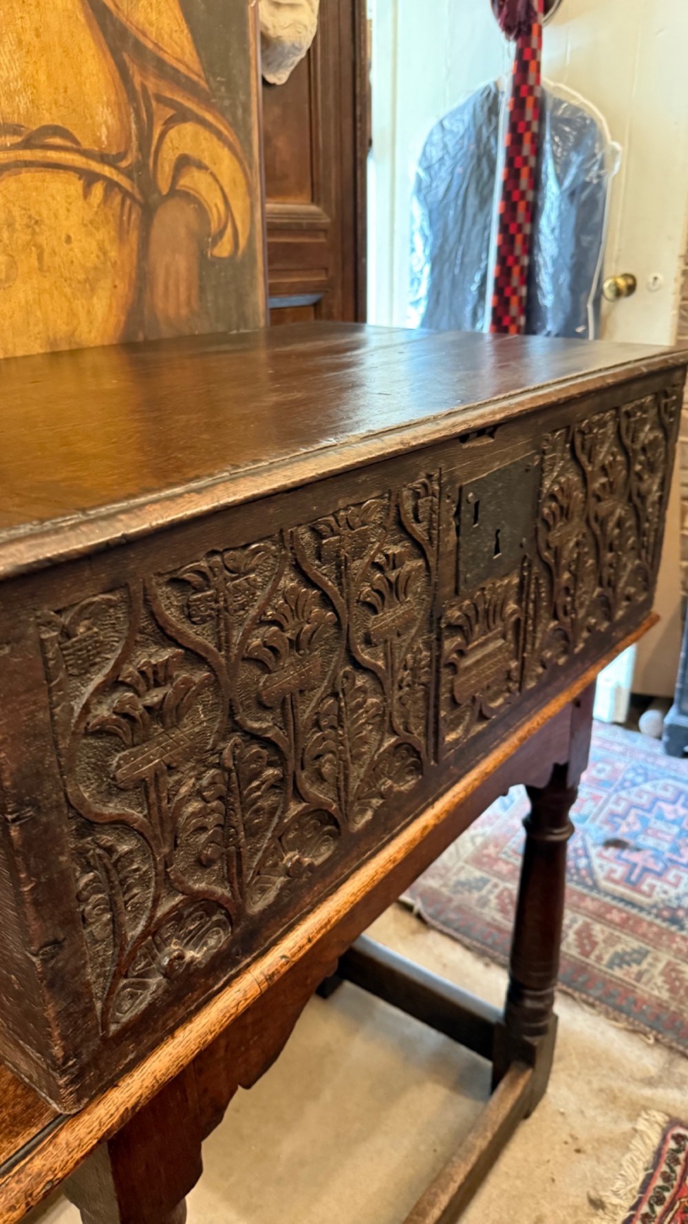 A 17th-century English oak bible box featuring relief carvings of foliate patterns across the front panel and a central iron lock plate. View IV
