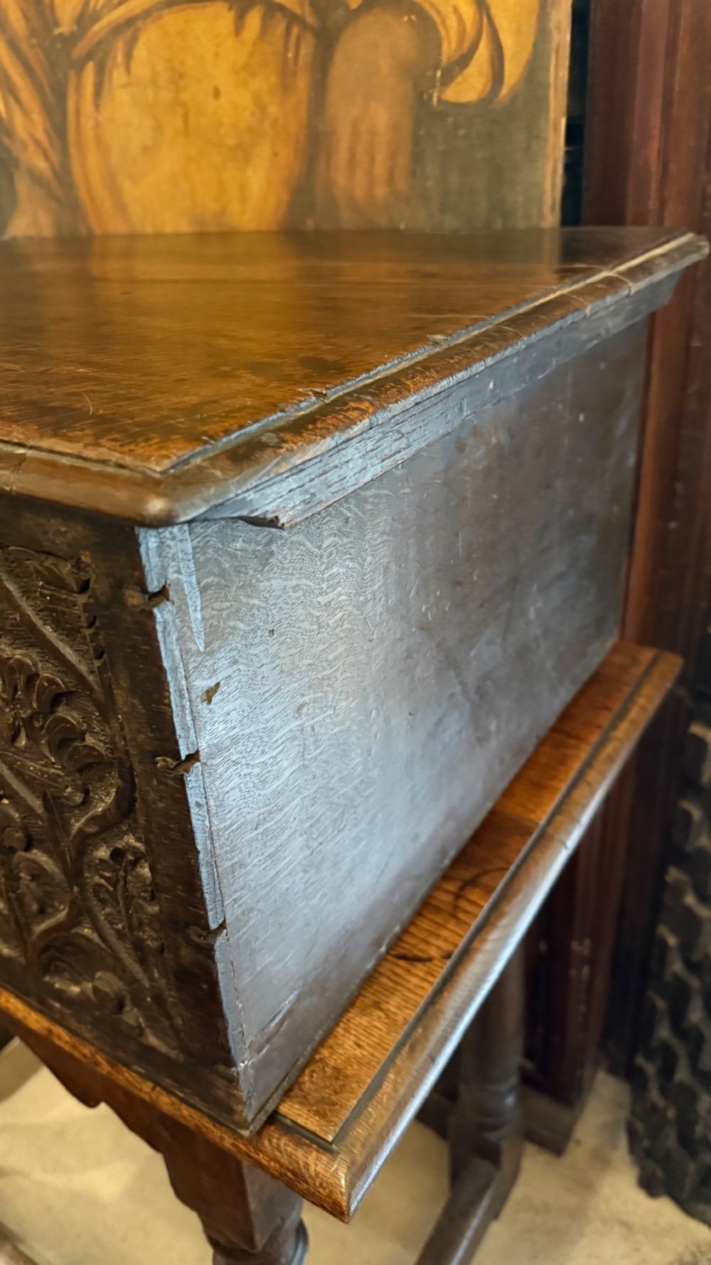 A 17th-century English oak bible box featuring relief carvings of foliate patterns across the front panel and a central iron lock plate. View X