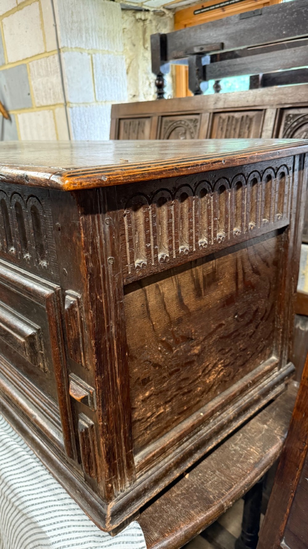 A 17th-century dark oak coffer featuring carved arcaded detail above geometrically moulded panel fronts and a central iron keyhole escutcheon. View II