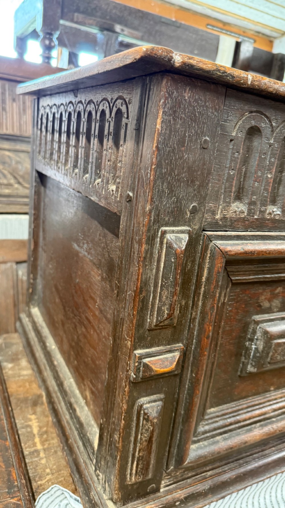 A 17th-century dark oak coffer featuring carved arcaded detail above geometrically moulded panel fronts and a central iron keyhole escutcheon. View X