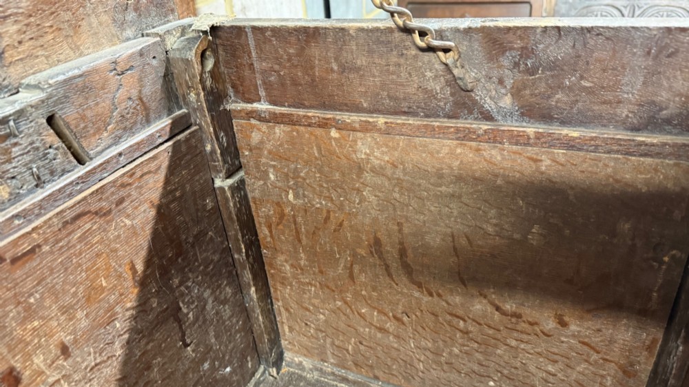 A 17th-century dark oak coffer featuring carved arcaded detail above geometrically moulded panel fronts and a central iron keyhole escutcheon. View XIV