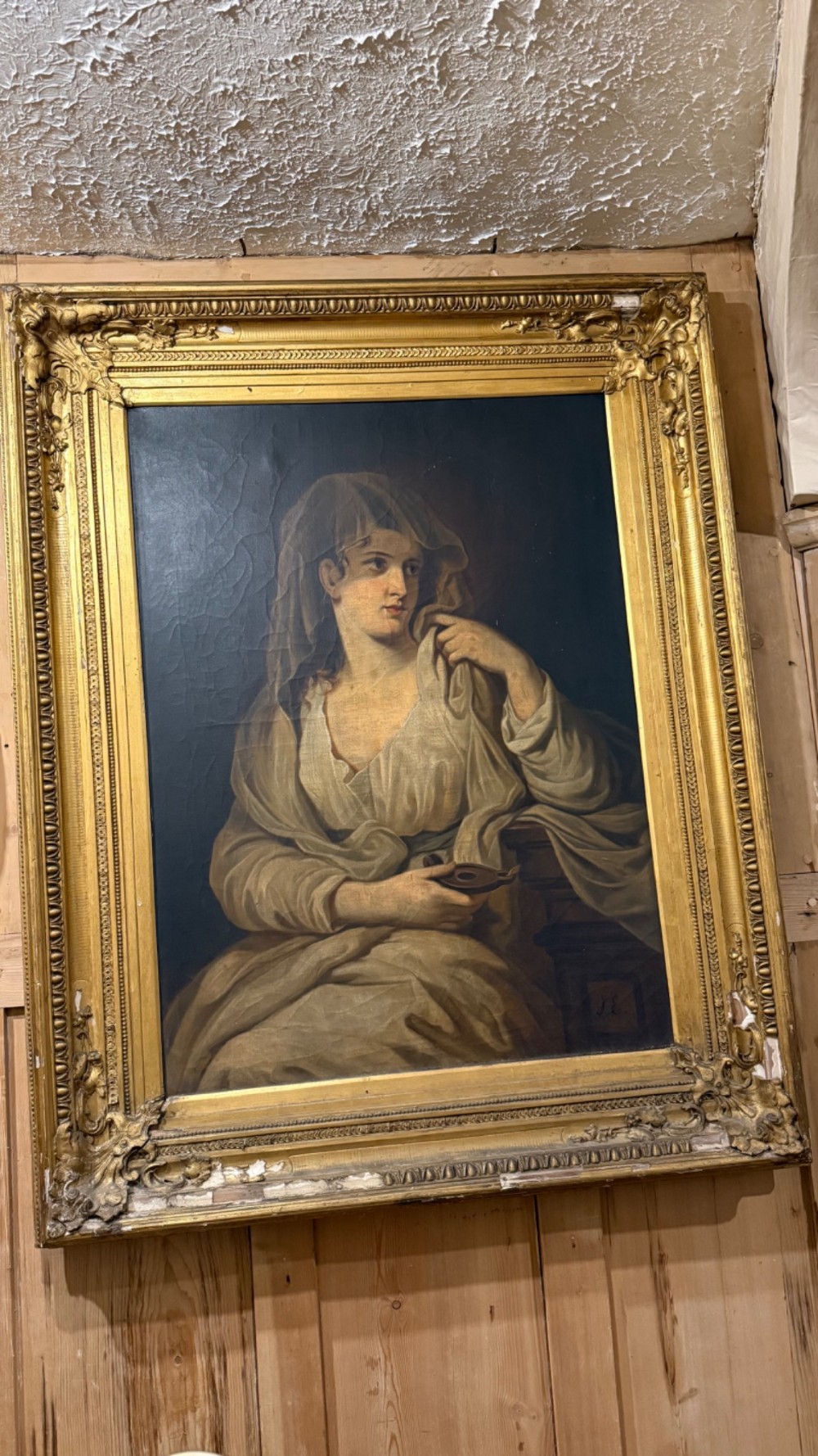 A nineteenth-century oil portrait of a draped woman holding a small lamp, housed within an ornate gilded frame. View II