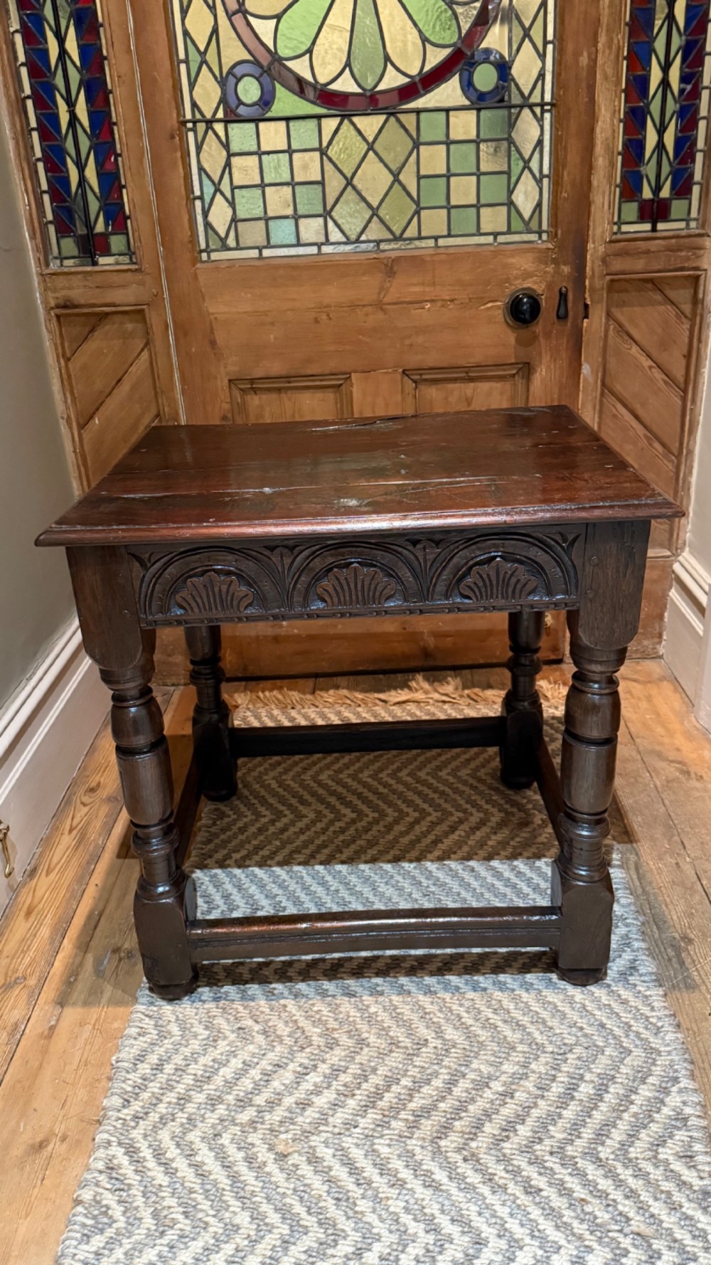 A dark oak 17th-century centre table featuring a carved fan-pattern apron, turned baluster legs, and sturdy wooden stretchers.