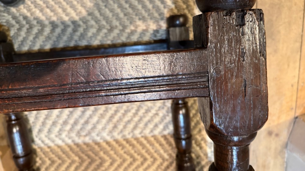 A dark oak 17th-century centre table featuring a carved fan-pattern apron, turned baluster legs, and sturdy wooden stretchers. View XII