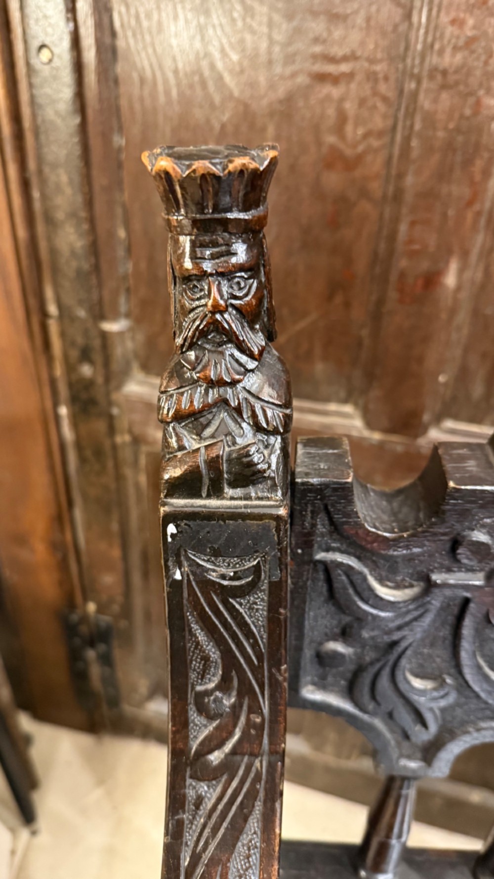A 19th-century dark carved oak X-frame armchair featuring a foliate backrest, turned balusters, and carved head finials. View VII