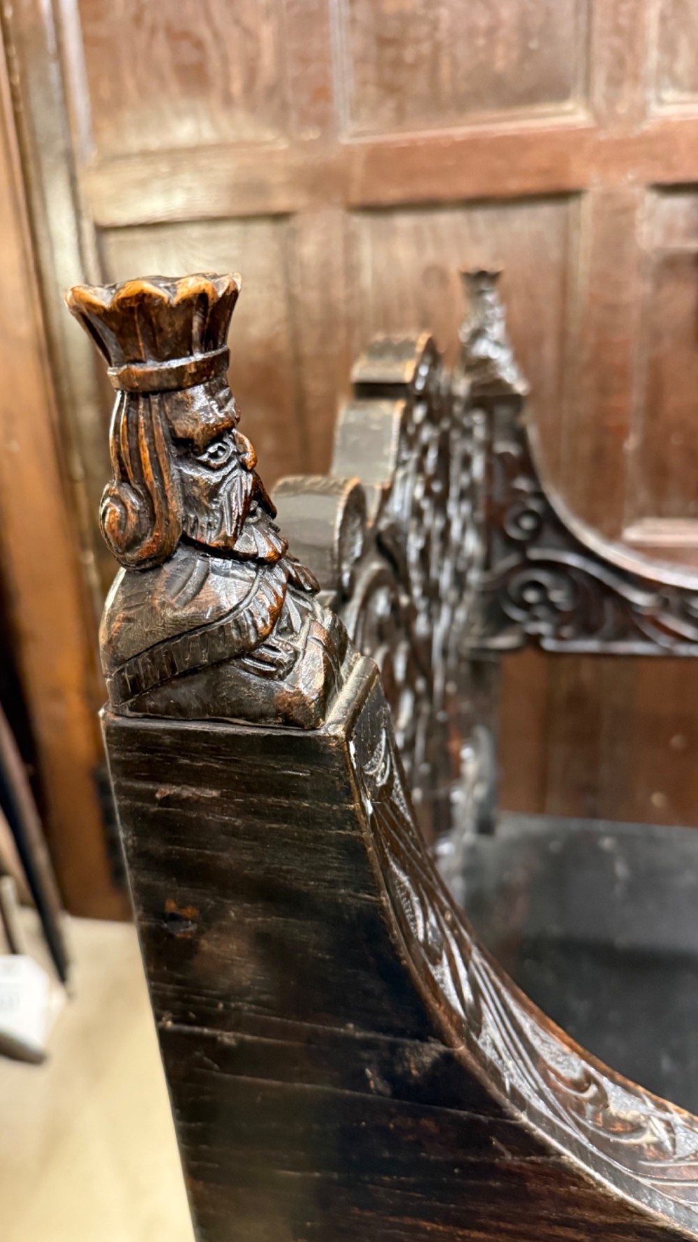 A 19th-century dark carved oak X-frame armchair featuring a foliate backrest, turned balusters, and carved head finials. View IX