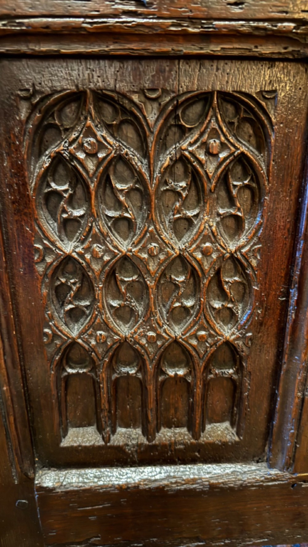 A dark brown 16th-century oak coffer featuring three front panels carved with gothic tracery and a central iron lockplate. View II