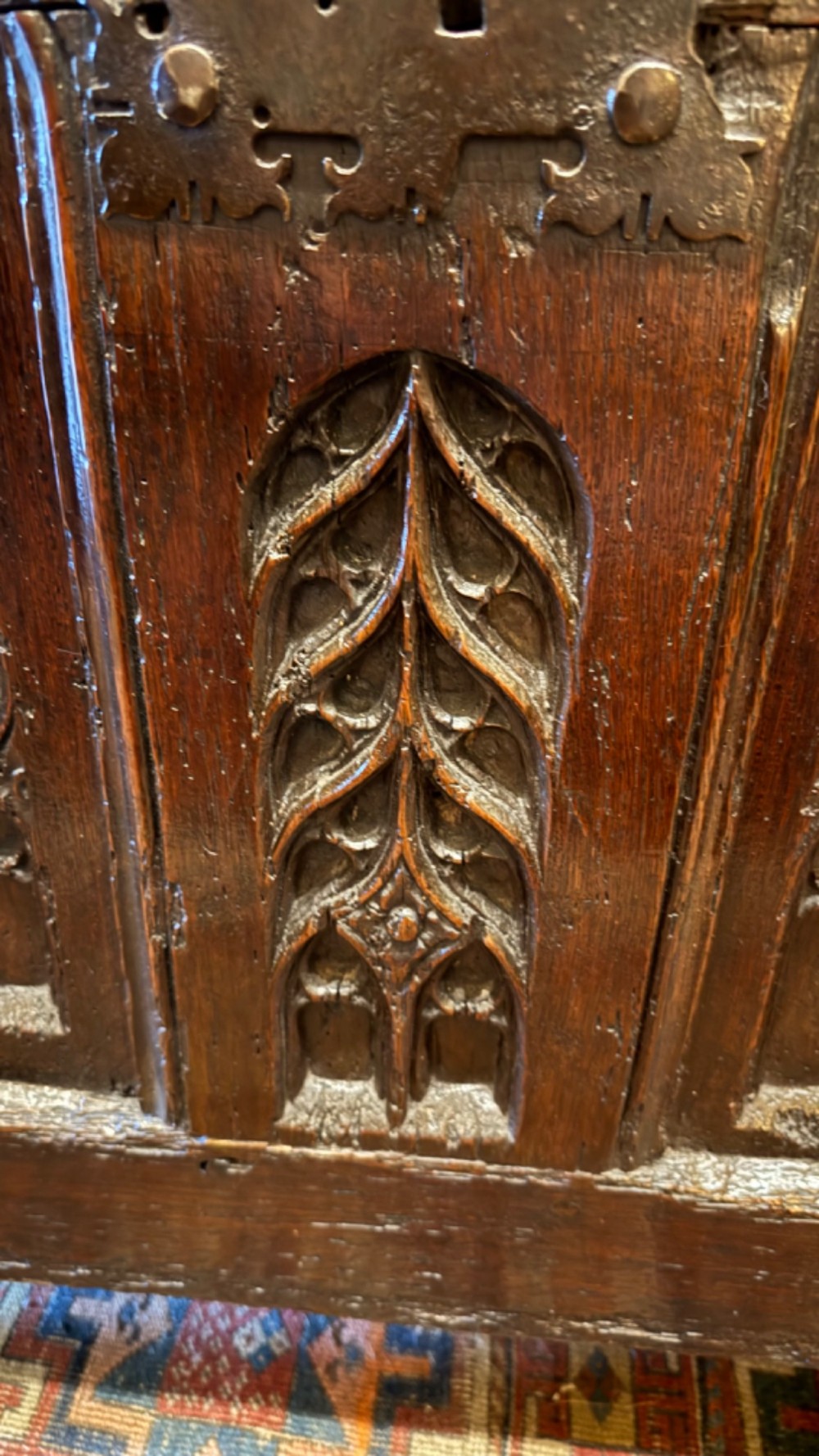 A dark brown 16th-century oak coffer featuring three front panels carved with gothic tracery and a central iron lockplate. View III