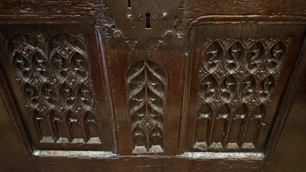 A dark brown 16th-century oak coffer featuring three front panels carved with gothic tracery and a central iron lockplate. View VI