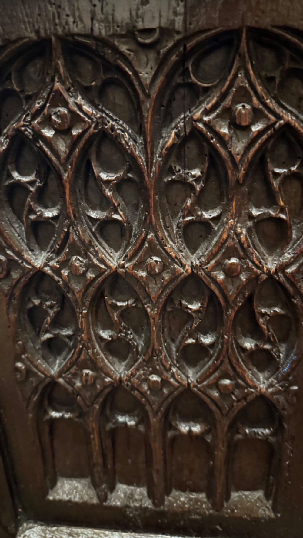 A dark brown 16th-century oak coffer featuring three front panels carved with gothic tracery and a central iron lockplate. View IX
