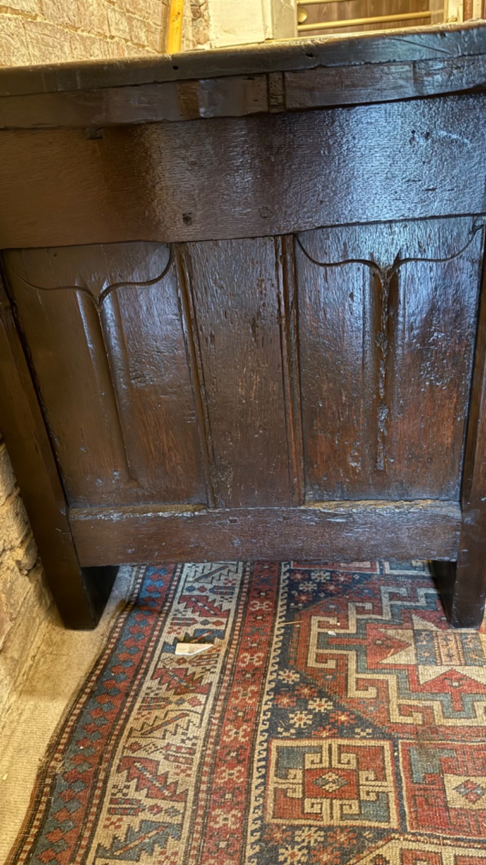 A dark brown 16th-century oak coffer featuring three front panels carved with gothic tracery and a central iron lockplate. View X