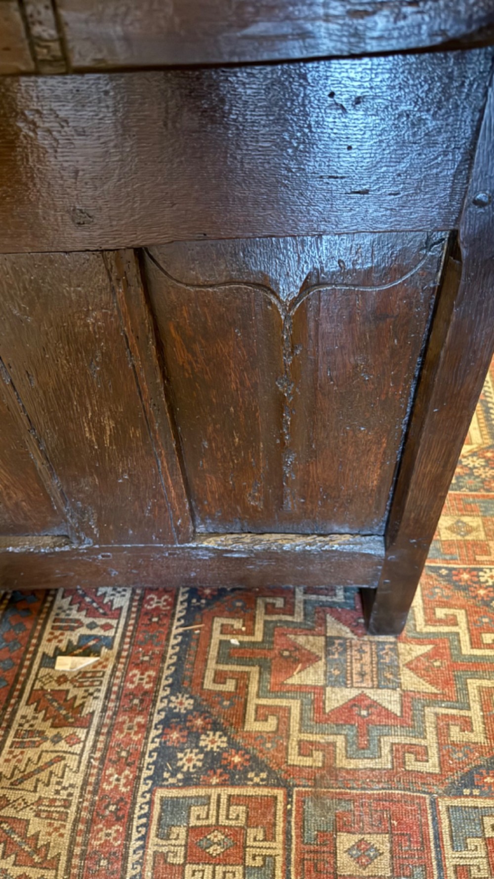 A dark brown 16th-century oak coffer featuring three front panels carved with gothic tracery and a central iron lockplate. View XI