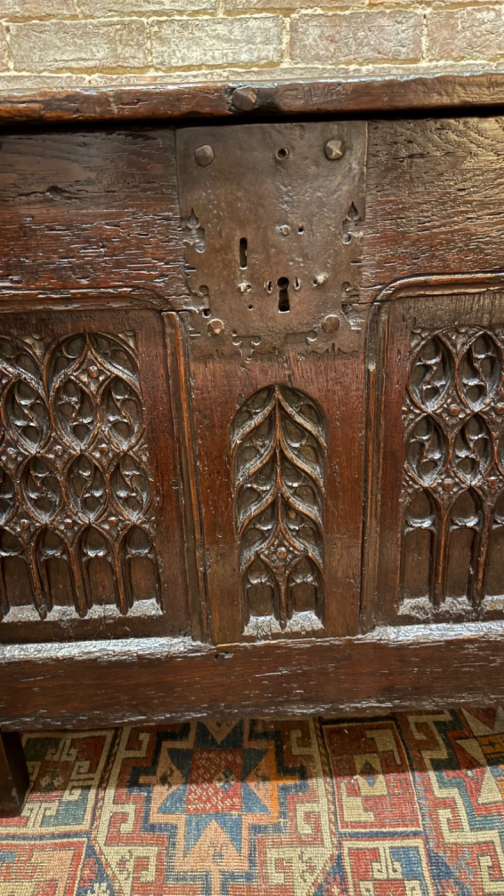 A dark brown 16th-century oak coffer featuring three front panels carved with gothic tracery and a central iron lockplate. View XII