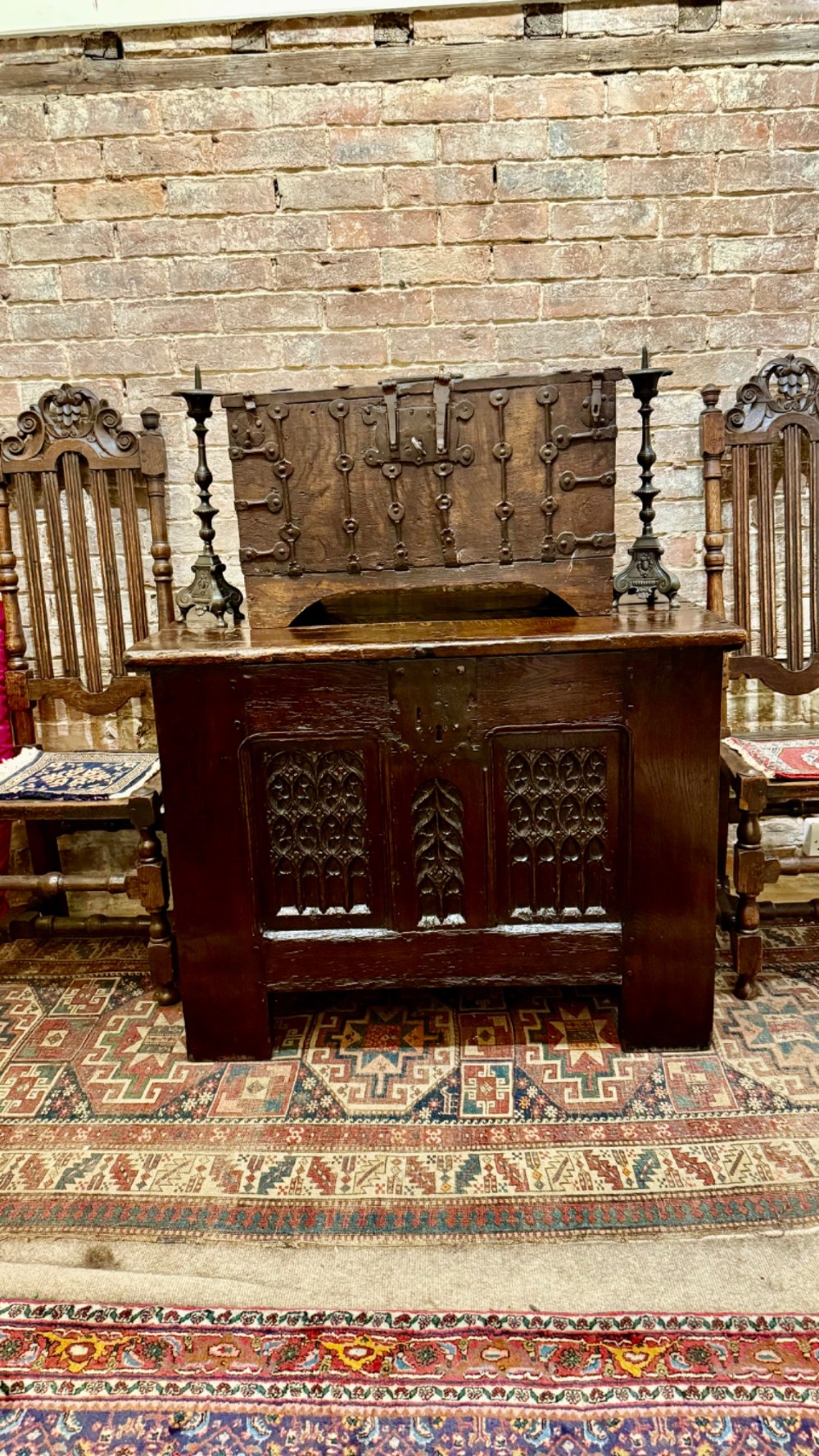 A dark brown 16th-century oak coffer featuring three front panels carved with gothic tracery and a central iron lockplate. View XV