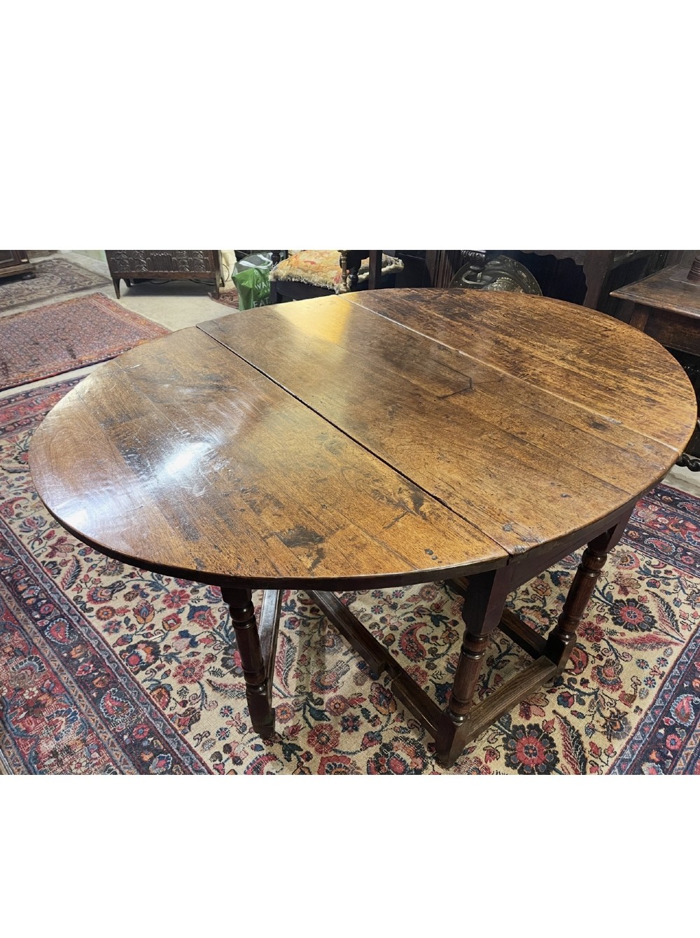 An 18th-century walnut gateleg table featuring an oval drop-leaf top supported by turned legs. View II