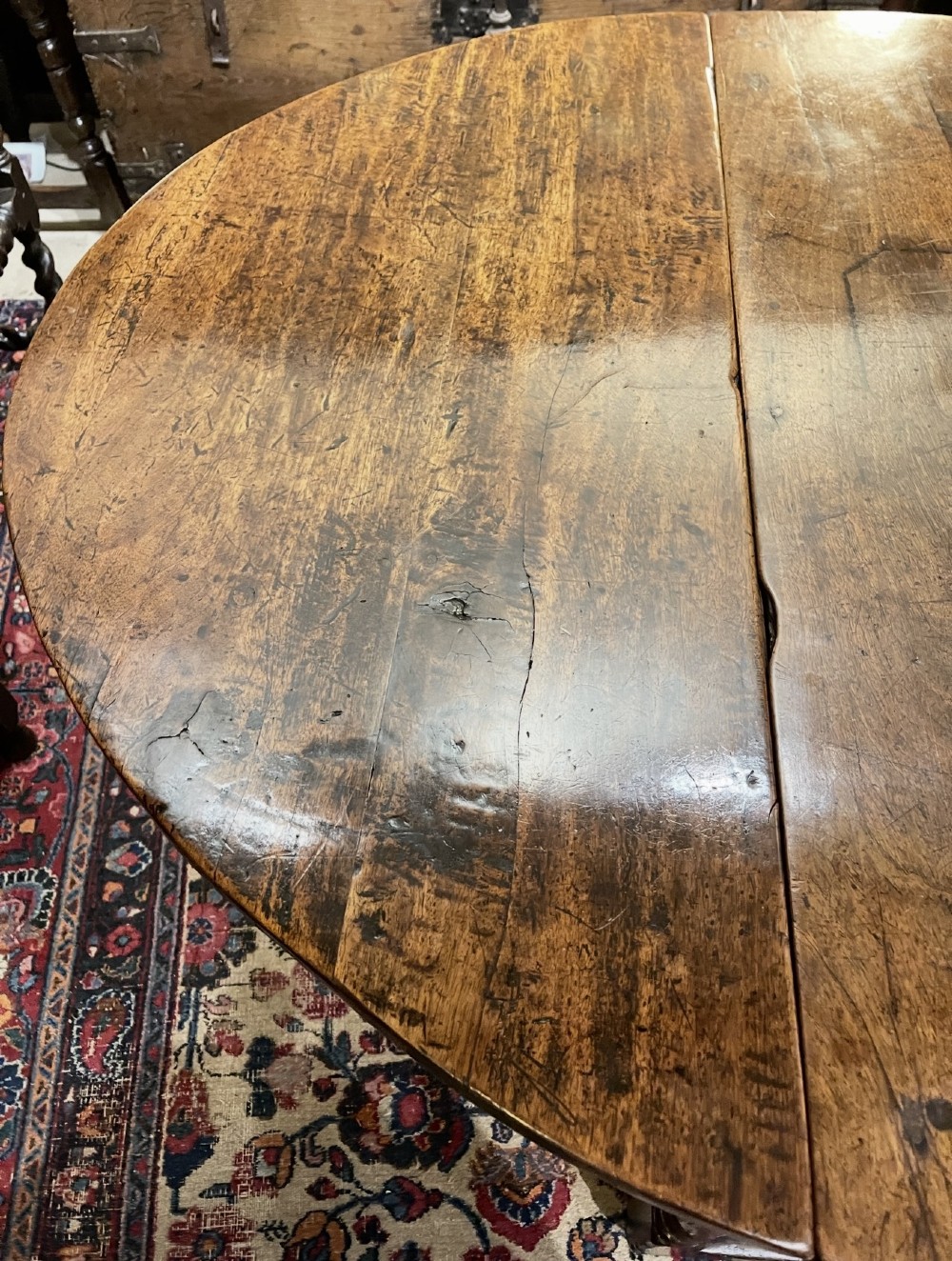 An 18th-century walnut gateleg table featuring an oval drop-leaf top supported by turned legs. View V