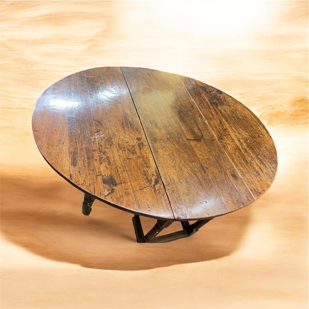 An 18th-century walnut gateleg table featuring an oval drop-leaf top supported by turned legs. View IX