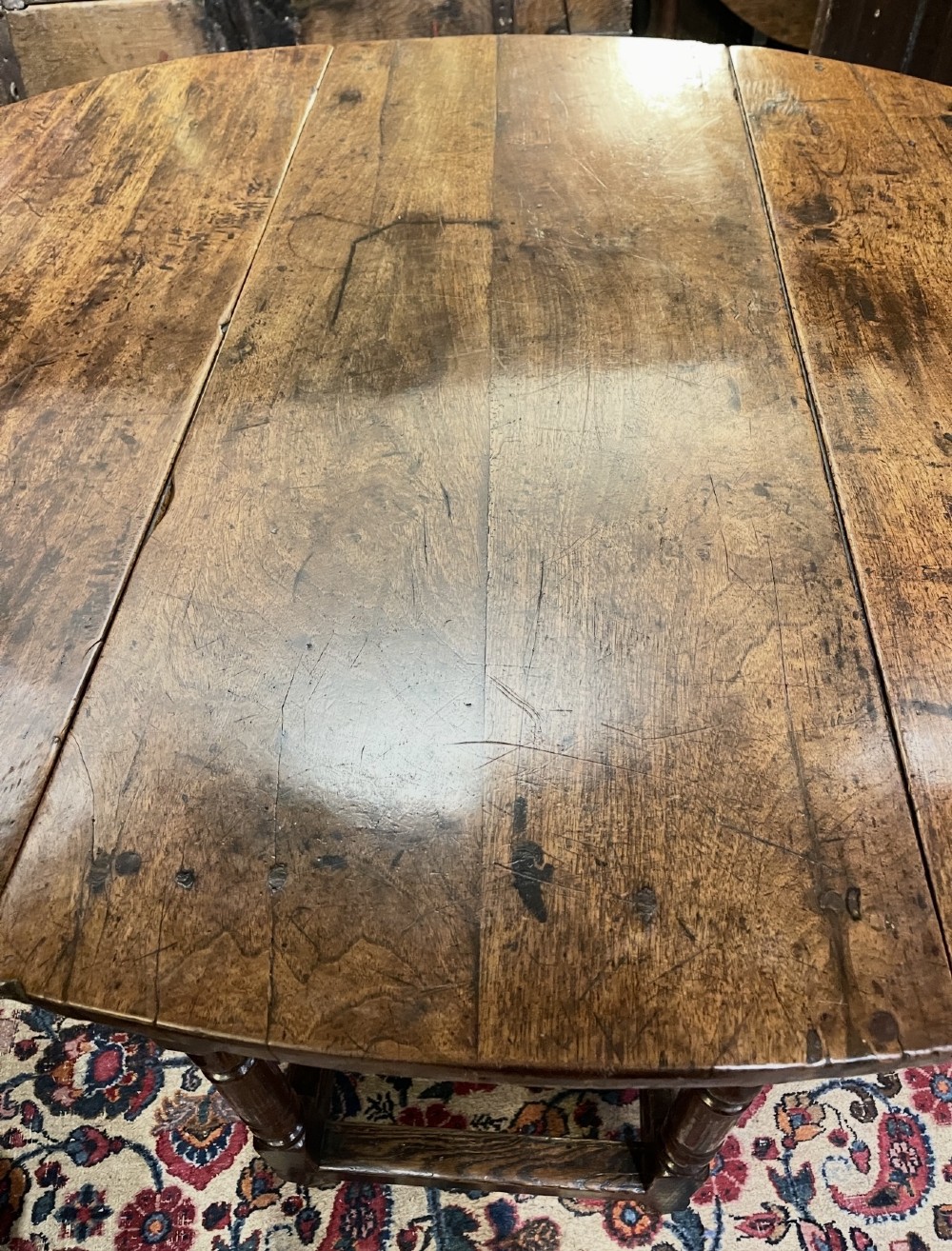 An 18th-century walnut gateleg table featuring an oval drop-leaf top supported by turned legs. View X