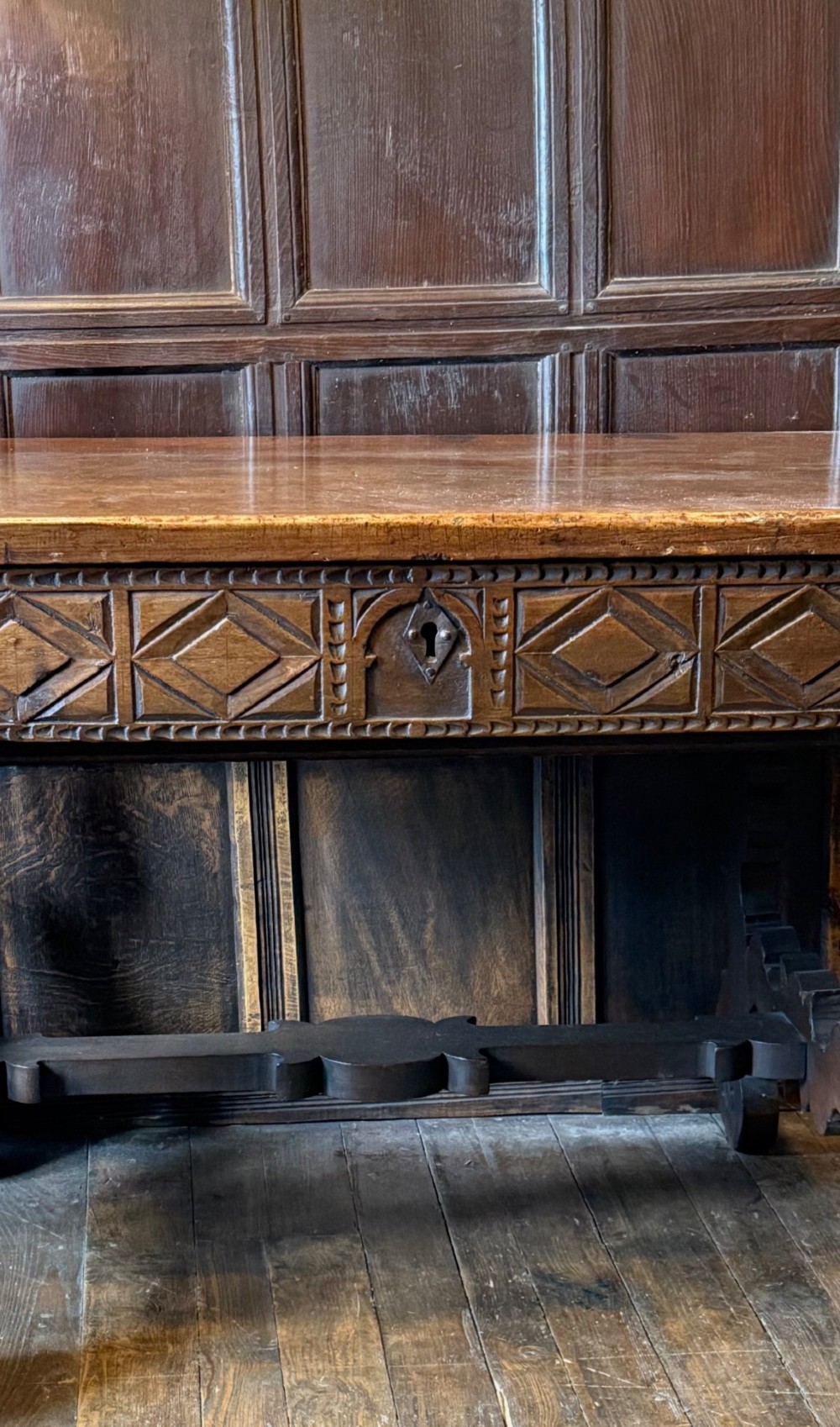 A 17th-century dark walnut side table featuring a geometrically carved single drawer, detailed trestle end supports, and a shaped central stretcher. View IV