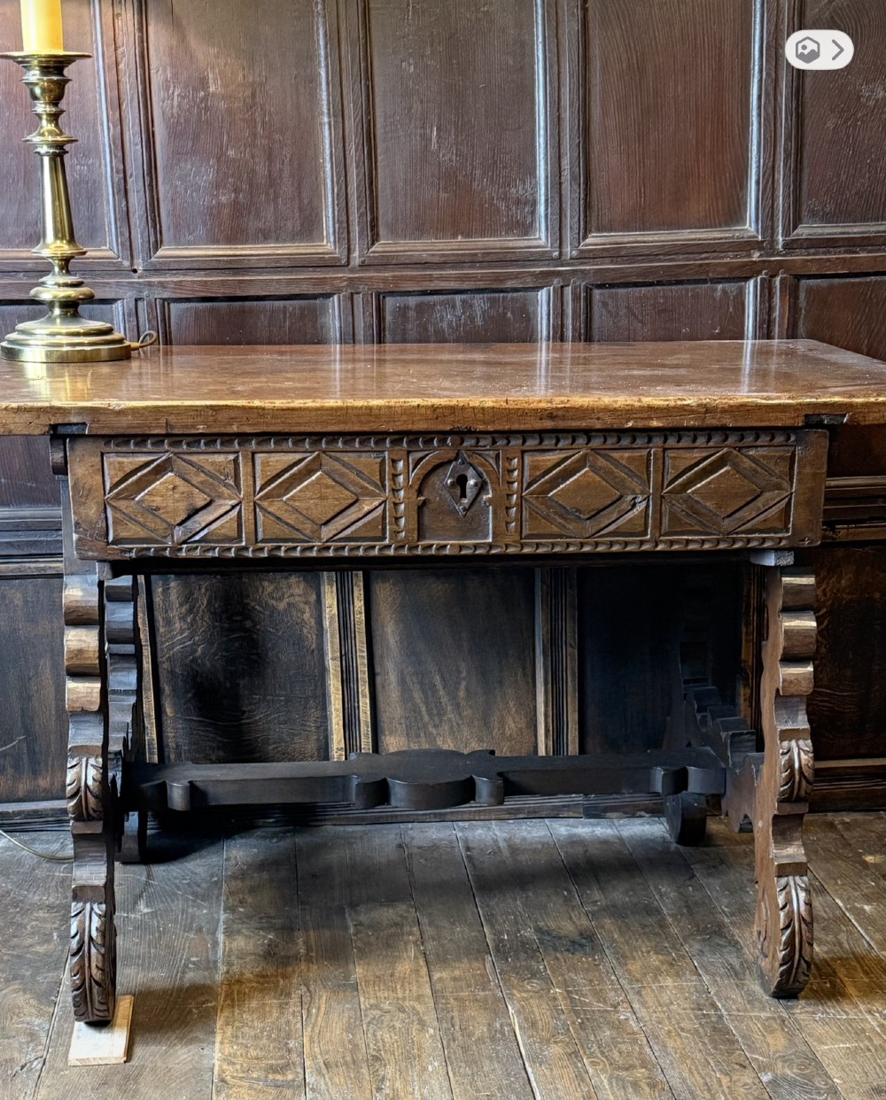 A 17th-century dark walnut side table featuring a geometrically carved single drawer, detailed trestle end supports, and a shaped central stretcher. View V