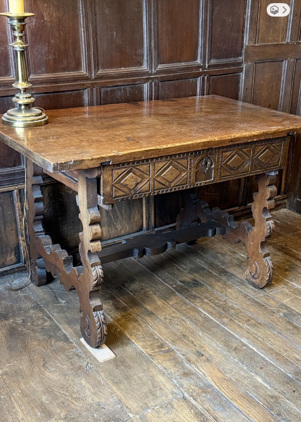 A 17th-century dark walnut side table featuring a geometrically carved single drawer, detailed trestle end supports, and a shaped central stretcher. View VII