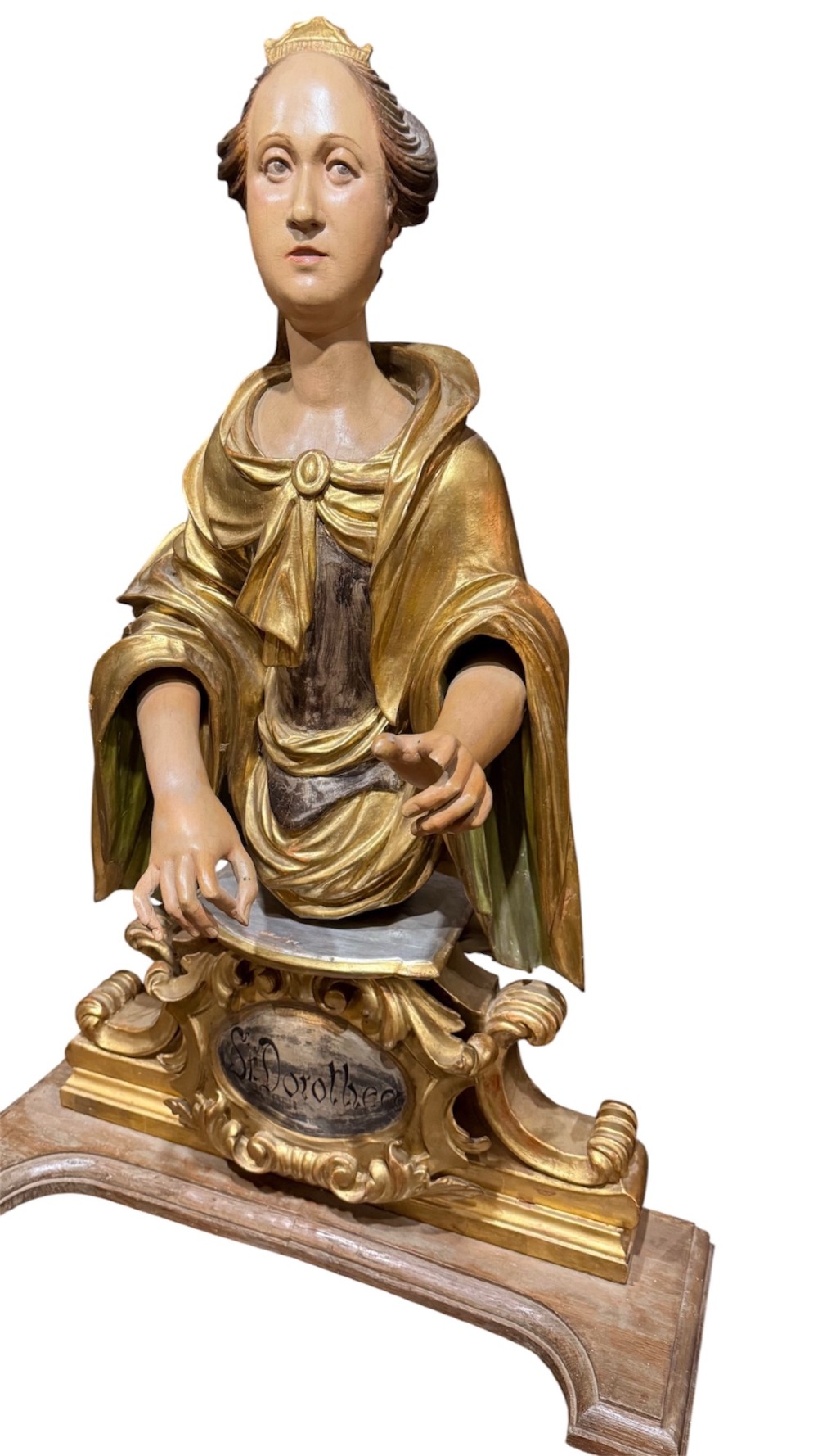 A seventeenth-century carved wooden bust of Saint Dorothea featuring gilded drapery and polychrome painted skin tones mounted on a decorative cartouche base.