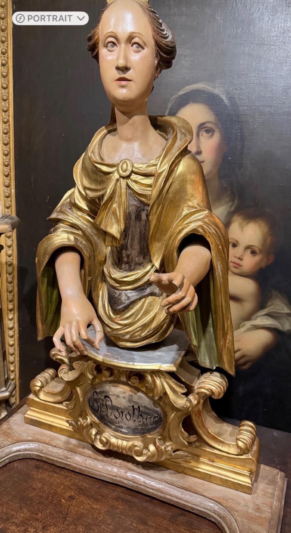 A seventeenth-century carved wooden bust of Saint Dorothea featuring gilded drapery and polychrome painted skin tones mounted on a decorative cartouche base. View III