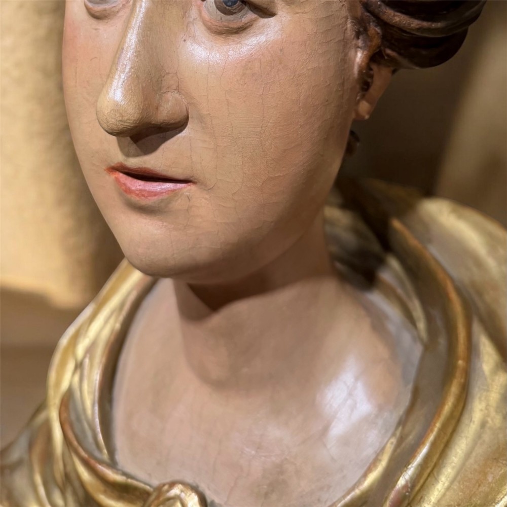 A seventeenth-century carved wooden bust of Saint Dorothea featuring gilded drapery and polychrome painted skin tones mounted on a decorative cartouche base. View VI