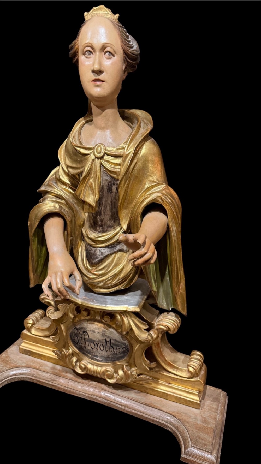 A seventeenth-century carved wooden bust of Saint Dorothea featuring gilded drapery and polychrome painted skin tones mounted on a decorative cartouche base. View VII