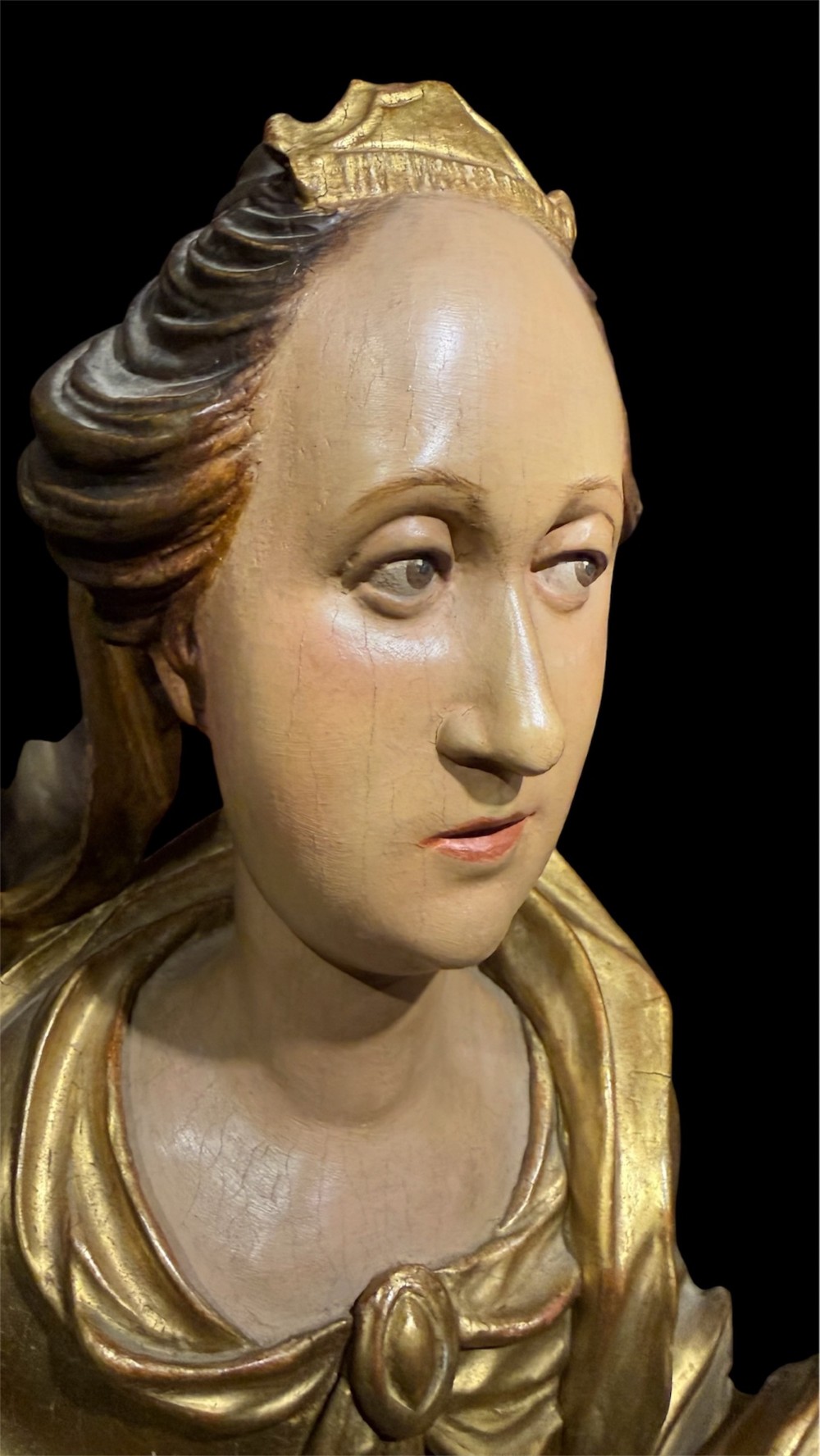 A seventeenth-century carved wooden bust of Saint Dorothea featuring gilded drapery and polychrome painted skin tones mounted on a decorative cartouche base. View XI