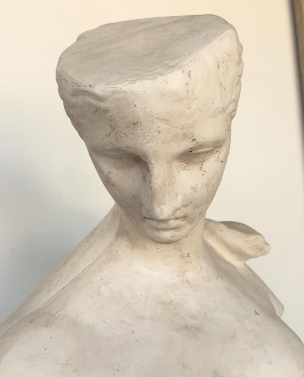 An off-white plaster bust depicting a classical head and torso in profile, angled downwards against a neutral background. View VIII