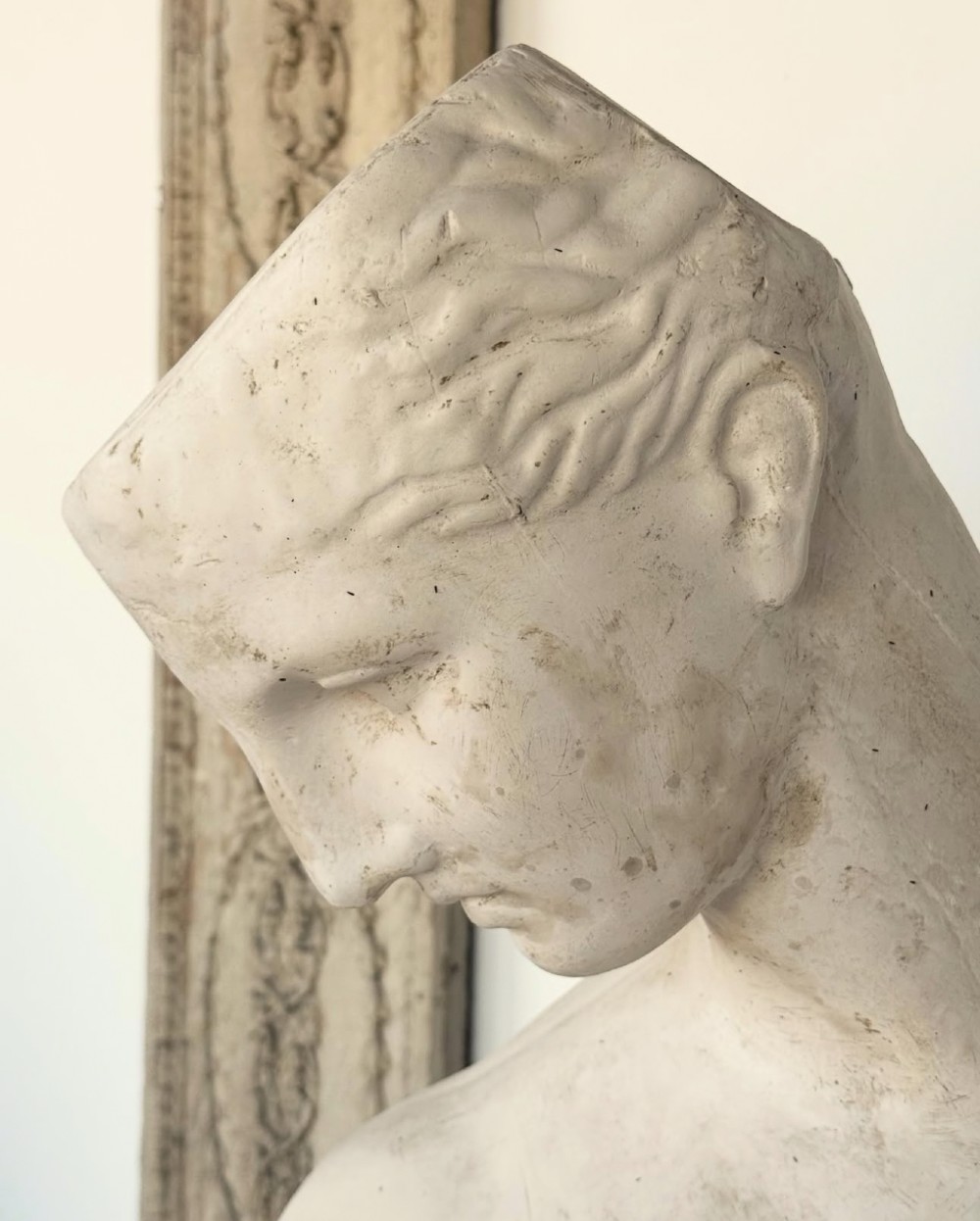 An off-white plaster bust depicting a classical head and torso in profile, angled downwards against a neutral background. View XI