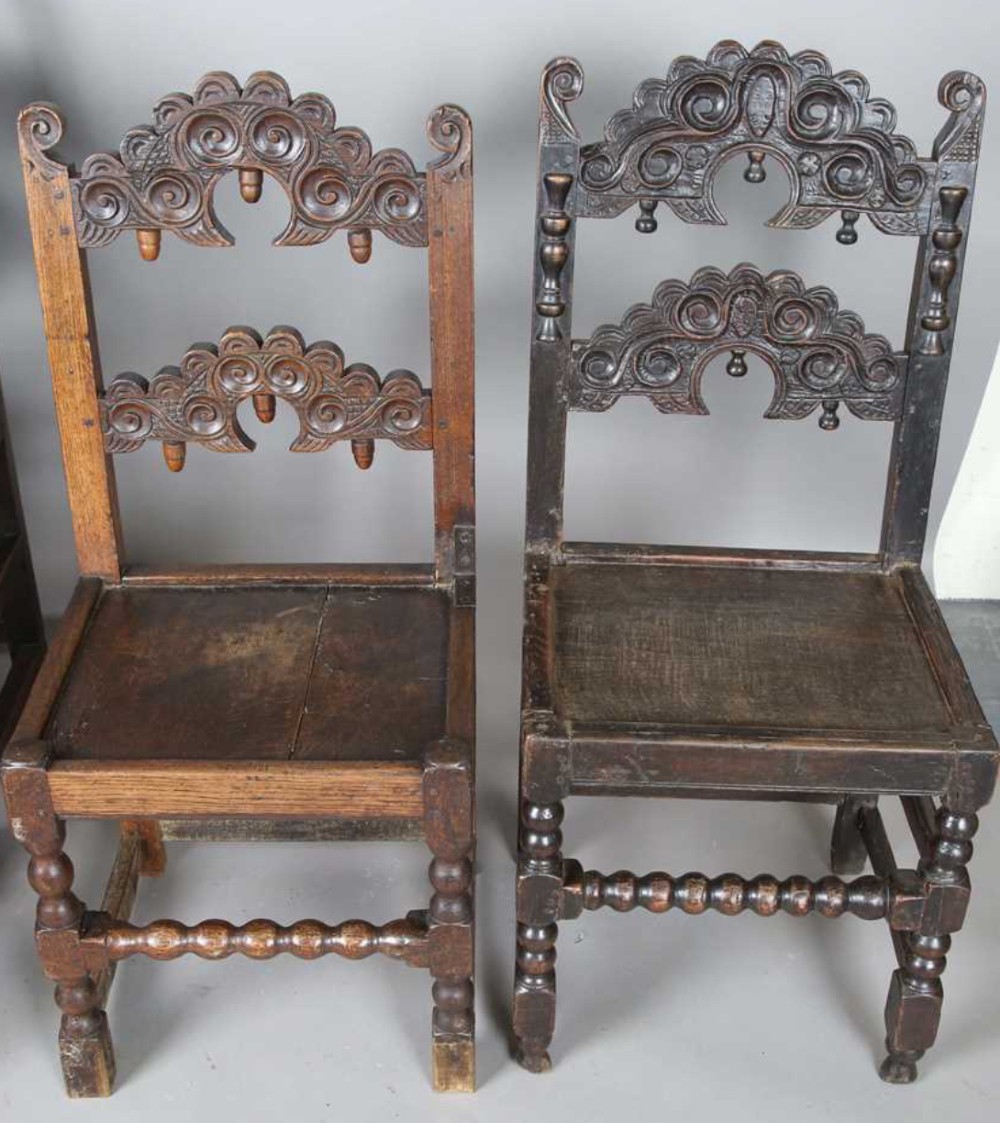 A set of dark carved oak dining chairs featuring carved openwork backs with scroll motifs, solid wooden seats, and turned front legs. View IV