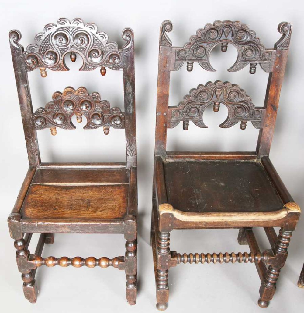 A set of dark carved oak dining chairs featuring carved openwork backs with scroll motifs, solid wooden seats, and turned front legs. View VI