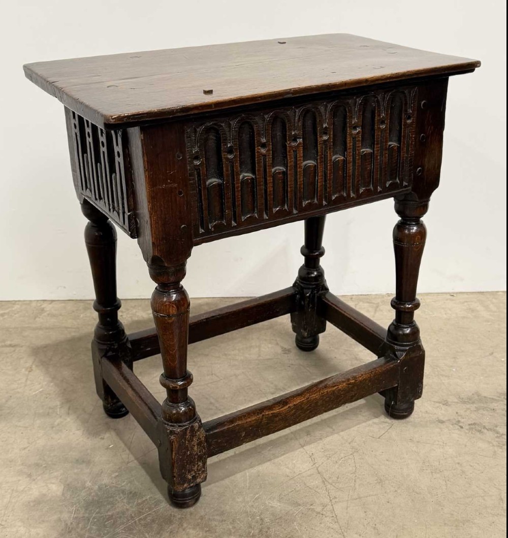 A 17th-century dark oak joint stool featuring a carved arcade frieze, turned legs, and sturdy base stretchers. View II