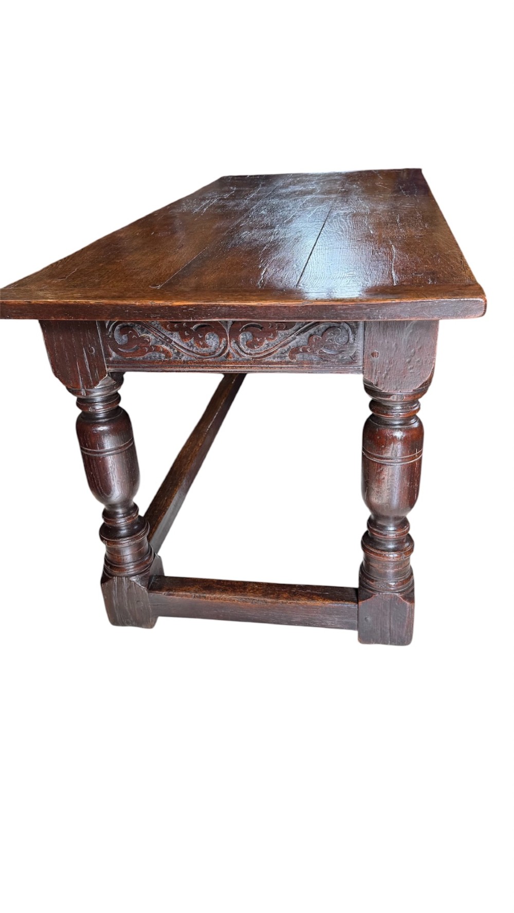 A 17th-century dark oak refectory dining table featuring a carved decorative frieze, turned baluster legs, and low perimeter stretchers. View II