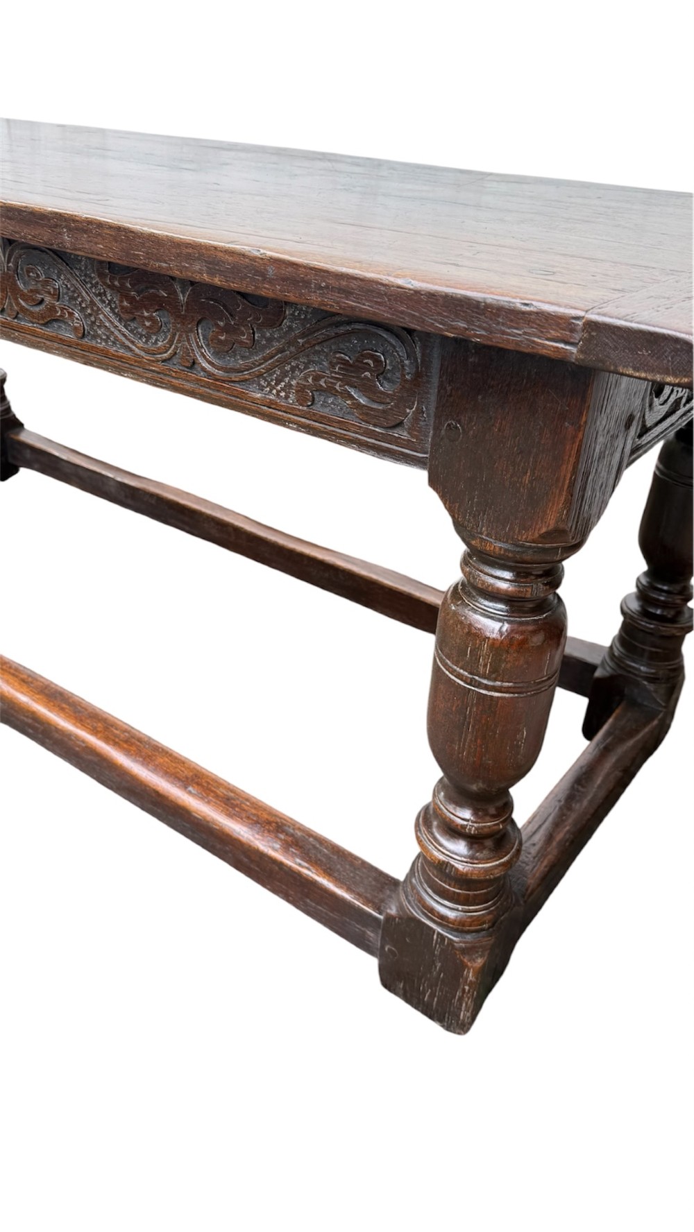 A 17th-century dark oak refectory dining table featuring a carved decorative frieze, turned baluster legs, and low perimeter stretchers. View III