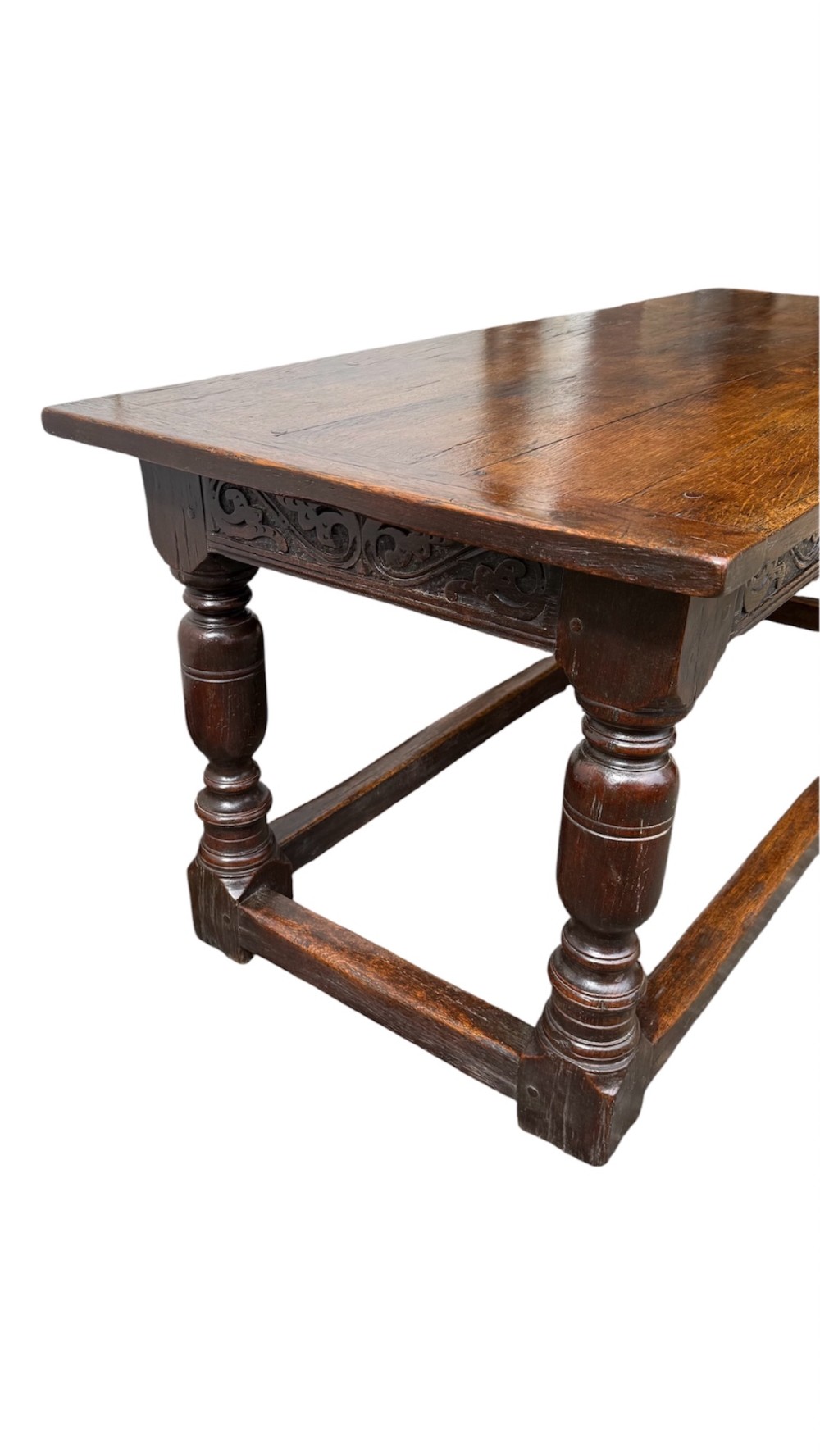 A 17th-century dark oak refectory dining table featuring a carved decorative frieze, turned baluster legs, and low perimeter stretchers. View IV