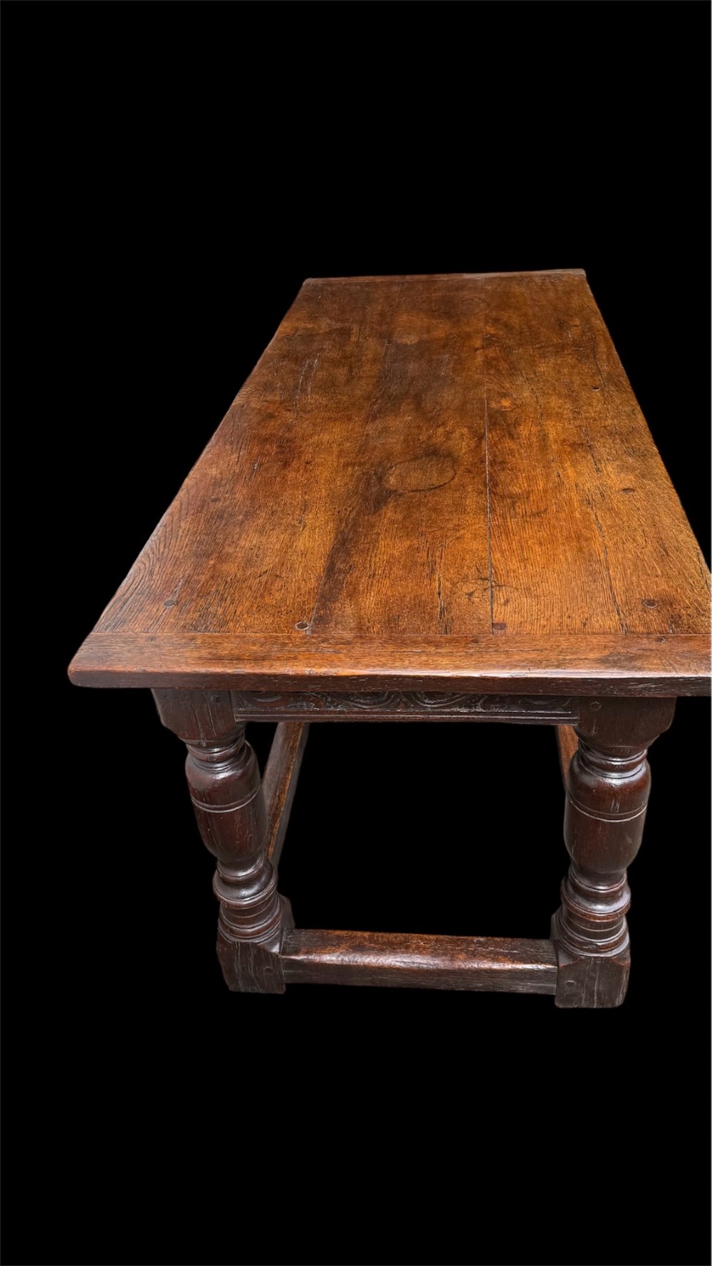 A 17th-century dark oak refectory dining table featuring a carved decorative frieze, turned baluster legs, and low perimeter stretchers. View IX