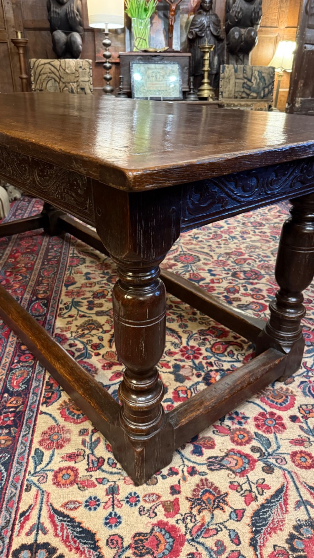 A 17th-century dark oak refectory dining table featuring a carved decorative frieze, turned baluster legs, and low perimeter stretchers. View XIV